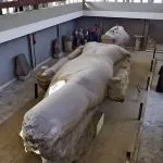 The monumental Colossus of Ramses II, a massive ancient Egyptian statue, lying in a museum in historic Memphis.