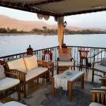 A sundeck lounge on a traditional wooden boat sailing the Nile River.