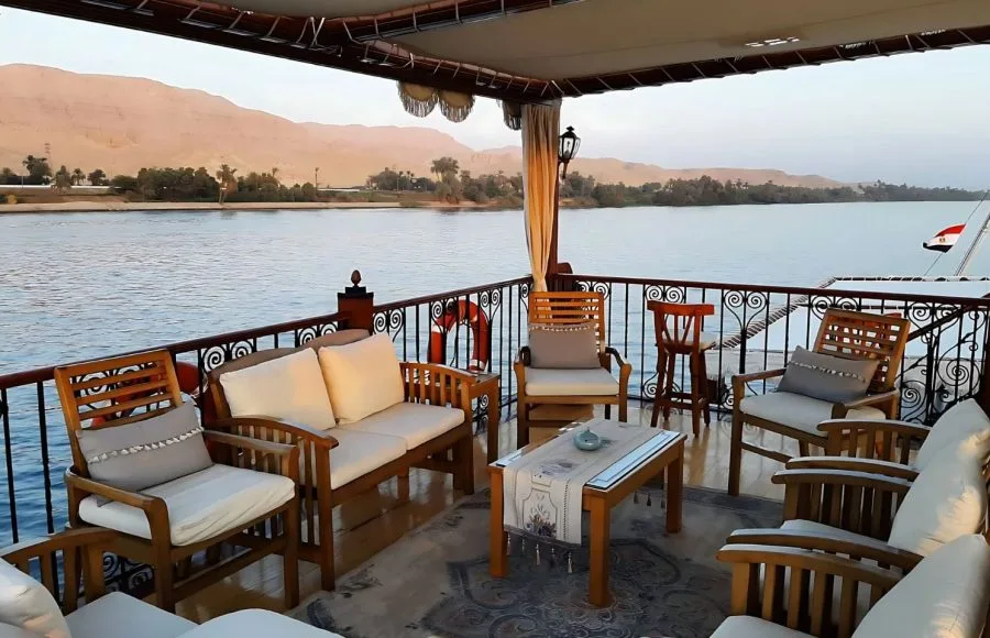 A sundeck lounge on a traditional wooden boat sailing the Nile River.