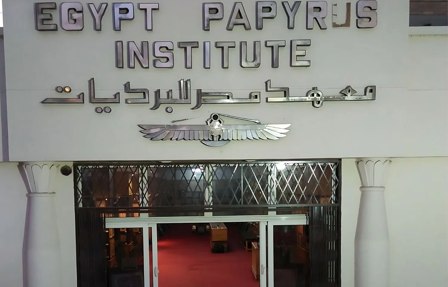 The exterior entrance sign of the Egypt Papyrus Institute featuring silver lettering and Egyptian motifs.