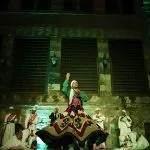 A Sufi dancer looking upward under atmospheric green lights at Wekalet El Ghouri.