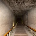 Long, steep wooden staircase leading into the dark entrance of the Royal Tomb of Akhenaten at Amarna, Egypt.