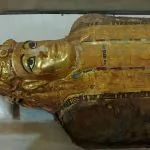 A close-up view of a Golden Mummy from the Greco-Roman period, covered in gold leaf and brightly painted plaster, displayed in the Museum of Oasis Bahariya, Egypt.