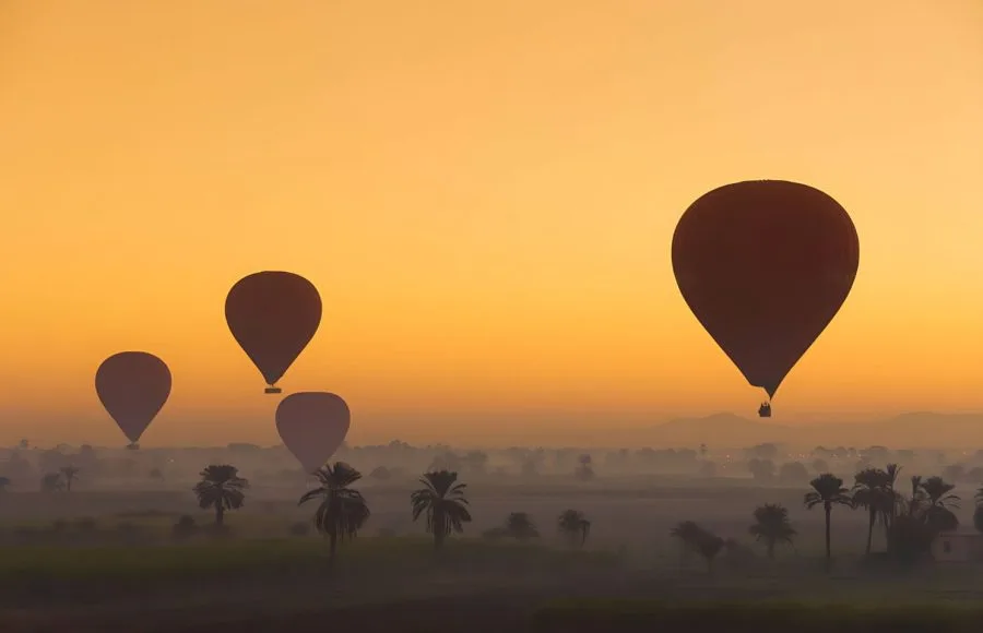Hot-Air-Balloons-Flying-At-Dawn-Over-The-Desert-Near-Luxor