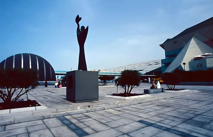 Modern sculpture and the distinct, sloping architecture of the Bibliotheca Alexandrina in Alexandria.
