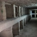 Dark subterranean passage and carved loculi (burial niches) inside the Roman-Egyptian Catacombs of Kom El Shoqafa in Alexandria.