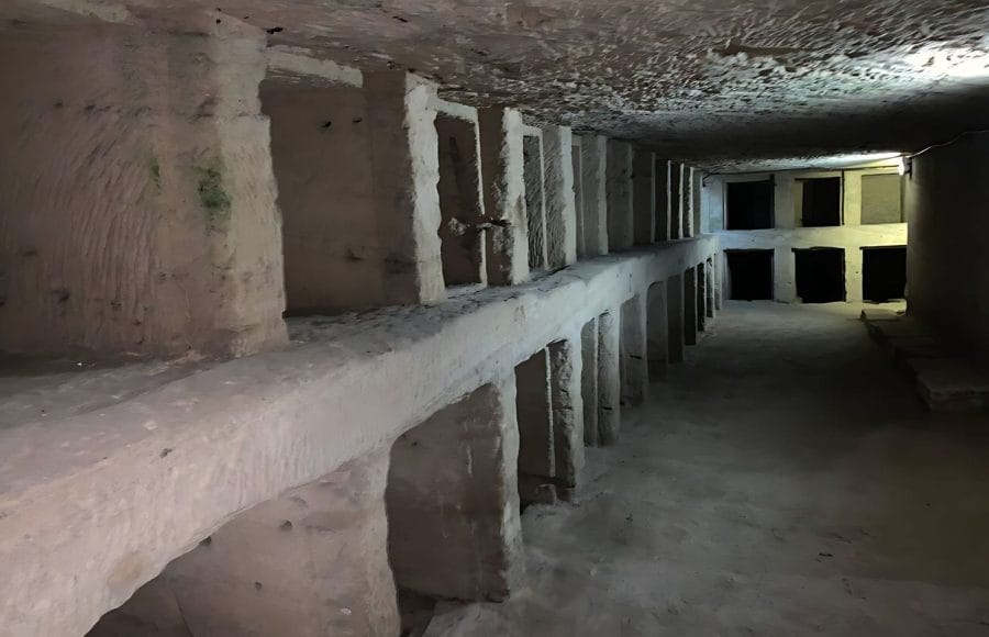Dark subterranean passage and carved loculi (burial niches) inside the Roman-Egyptian Catacombs of Kom El Shoqafa in Alexandria.