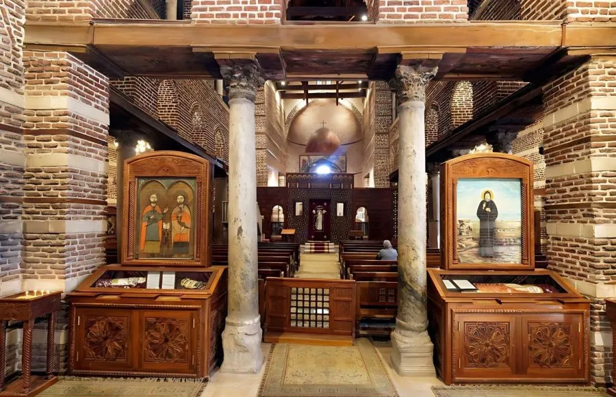 The ancient, intimate interior of the Inside View Church Of St Serge Egypt, showing the central nave, columns, wood beams, and Coptic icons.