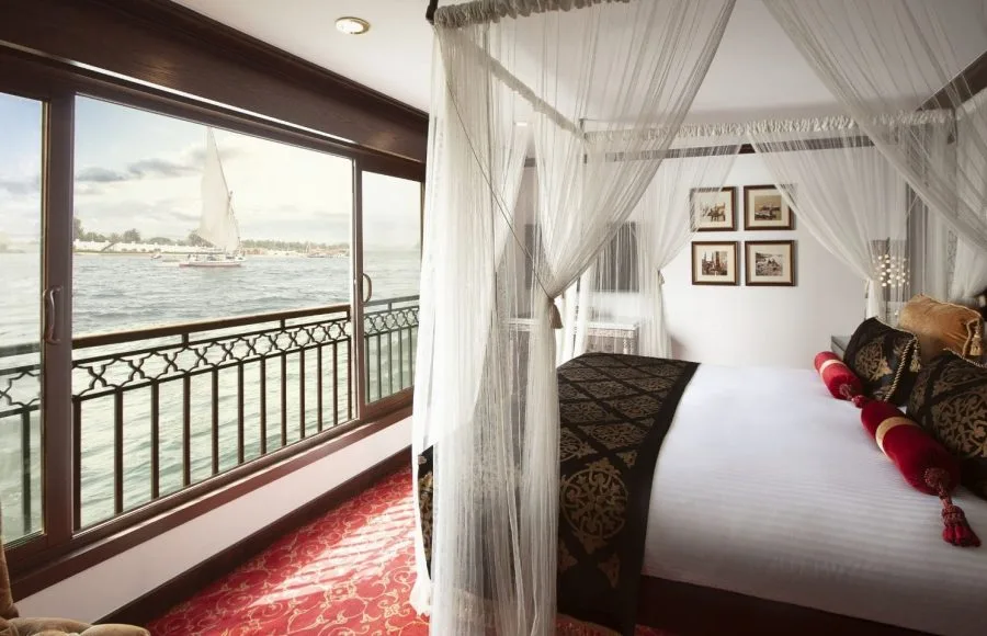 A luxurious suite aboard the Jaz Yakouta Dahabiya Nile Cruise with a view of the Nile River.