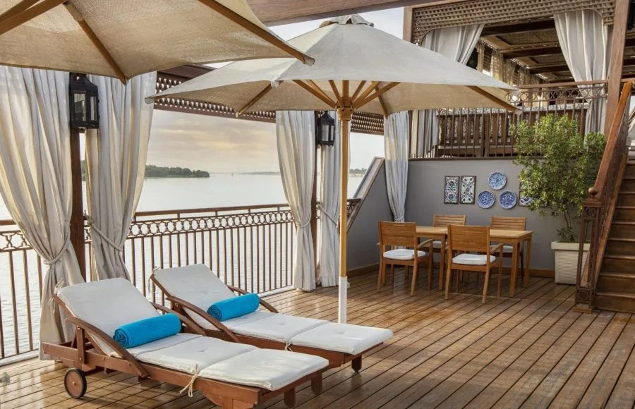 A relaxing sun deck view on the Jaz Yakouta Dahabiya Nile Cruise, featuring lounge chairs and umbrellas.