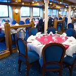 The dining room of the A Sara Nile Cruise, set with tables, and royal chairs.