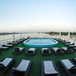 A view of the sun deck and swimming pool on the MS A Sara, with rows of lounge chairs and a beautiful view of the Nile.