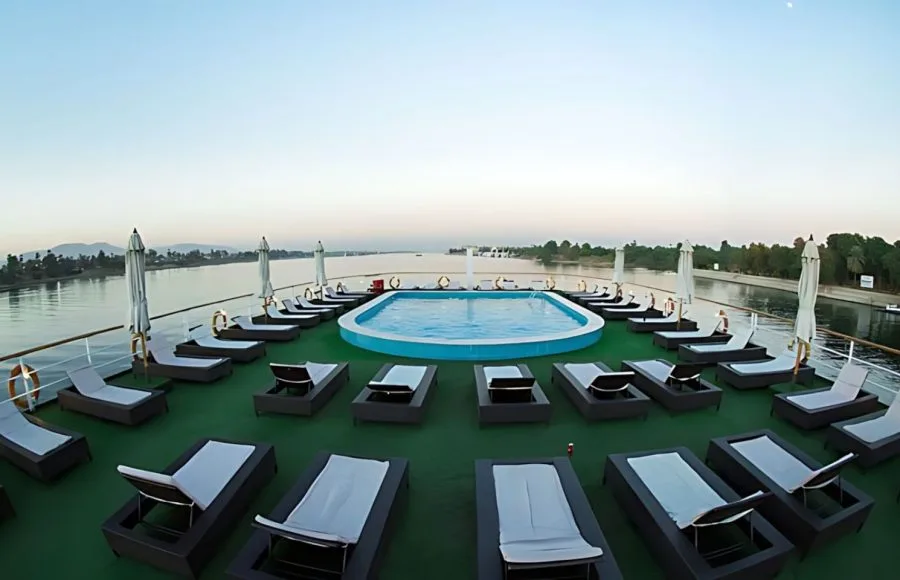 A view of the sun deck and swimming pool on the MS A Sara, with rows of lounge chairs and a beautiful view of the Nile.