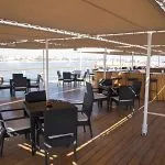 An outdoor dining area on the sun deck of the MS A Sara with a view of the Nile River.