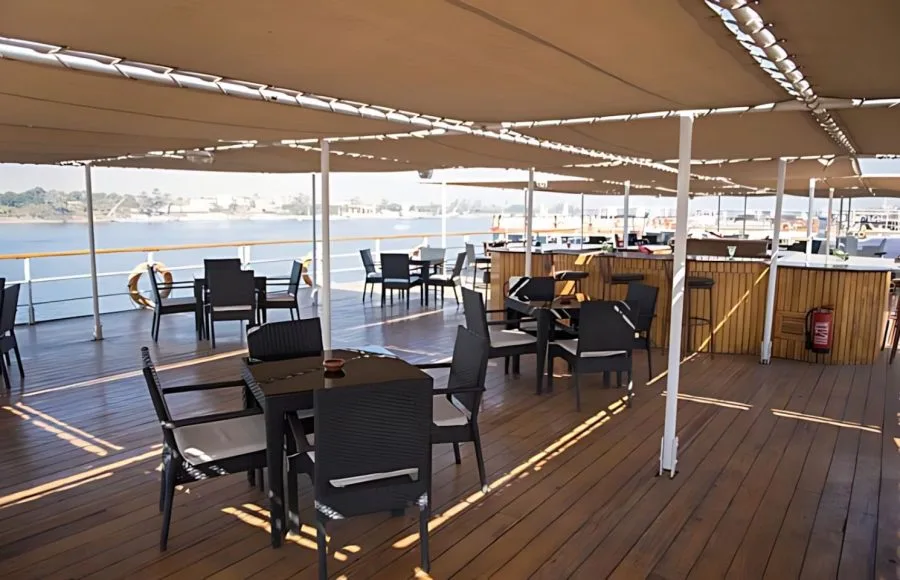An outdoor dining area on the sun deck of the MS A Sara with a view of the Nile River.