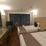 Twin-bed cruise ship cabin with a dressing table and viewing window.