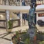 Ship lobby with marble floors, grand staircase, and classical female statue fountain.