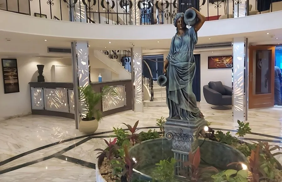 Ship lobby with marble floors, grand staircase, and classical female statue fountain.