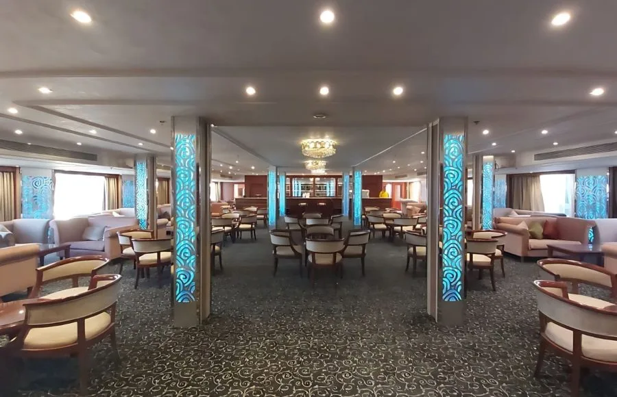 Elegant cruise ship lounge with armchairs, sofas, and illuminated pillars.