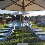 Cruise ship sundeck with blue striped loungers and a small pool under umbrellas.