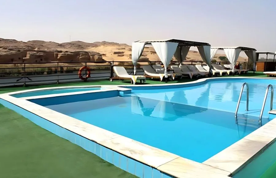 Cruise ship pool deck with cabanas and desert landscape background.