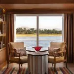 The elegant reading area of the Jaz Senator Nile Cruise, with two comfortable armchairs facing a large window with a scenic view of the Nile.