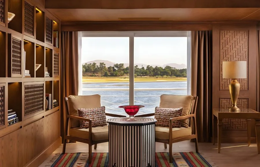 The elegant reading area of the Jaz Senator Nile Cruise, with two comfortable armchairs facing a large window with a scenic view of the Nile.