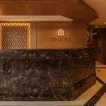 The elegant reception desk of the Jaz Senator Nile Cruise, featuring a dark marble countertop and intricate wooden decorative panels.