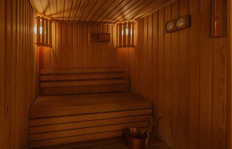 A warm and inviting sauna room on the Jaz Senator Nile Cruise, featuring wooden benches and walls, and soft lighting.