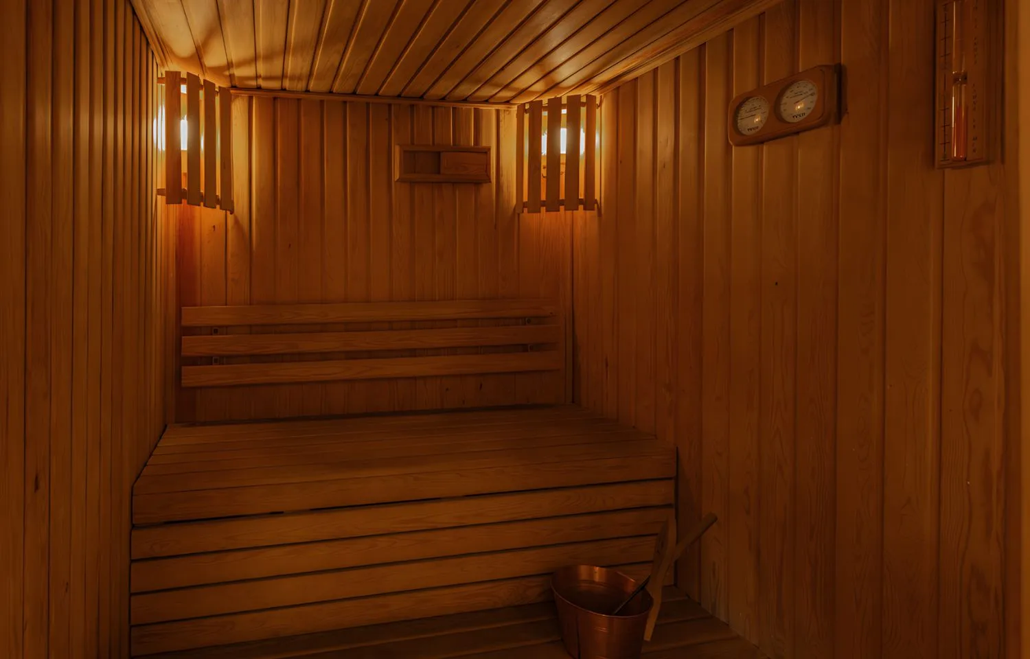 A warm and inviting sauna room on the Jaz Senator Nile Cruise, featuring wooden benches and walls, and soft lighting.