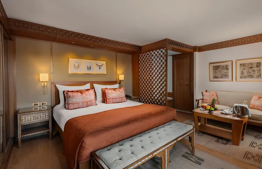 A luxurious suite on the Jaz Senator Nile Cruise, featuring a king-sized bed with rich fabrics, a seating area, and traditional Egyptian-inspired decor.