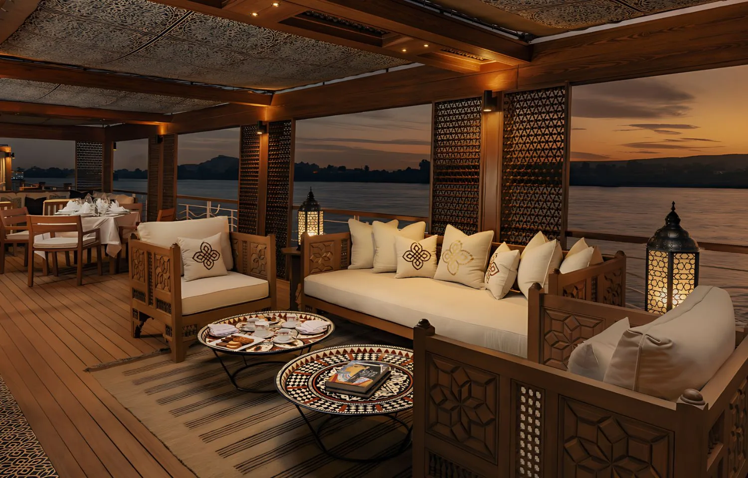 A beautifully decorated upper deck of the Jaz Senator Nile Cruise at sunset, featuring traditional Egyptian-style wooden furniture and lanterns.