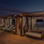 The sun deck of the Jaz Senator Nile Cruise at night, illuminated with soft lights, showing private cabanas with lounge beds overlooking the serene Nile.