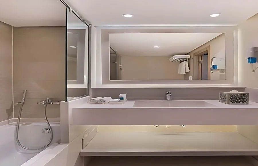 The clean and modern bathroom of a cabin on the Jaz Viceroy Nile Cruise, with a large mirror, a spacious countertop, and a shower with a glass partition.