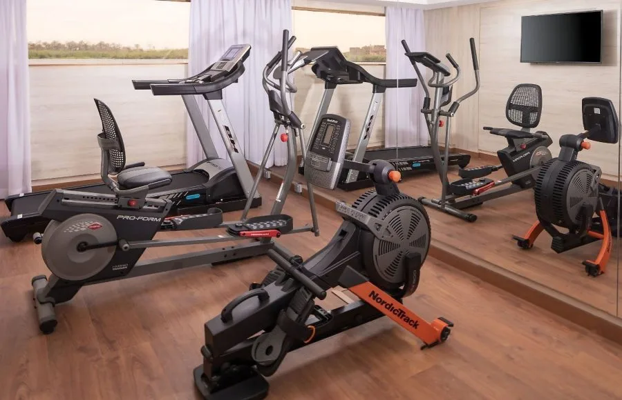 A modern gymnasium on the MS Jaz Viceroy Nile Cruise with various workout equipment, including treadmills, an elliptical, a stationary bike, and a rowing machine.