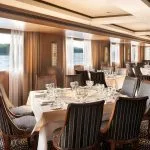 The elegant restaurant on the Jaz Viceroy Cruise, with tables set for dining and large windows offering views of the Nile River.