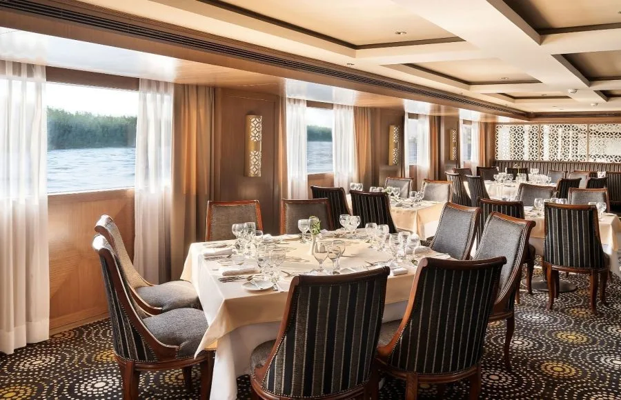 The elegant restaurant on the Jaz Viceroy Cruise, with tables set for dining and large windows offering views of the Nile River.