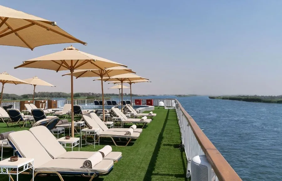 The sun deck of the Jaz Viceroy Cruise, showing a row of lounge chairs and umbrellas alongside the Nile River.