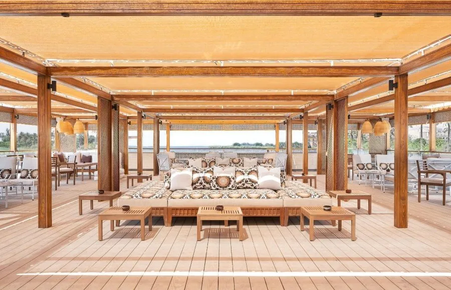 A view of the upper deck lounge of the MS Jaz Viceroy Nile Cruise, with a large, comfortable daybed-style seating area in the center and other lounge furniture around it.