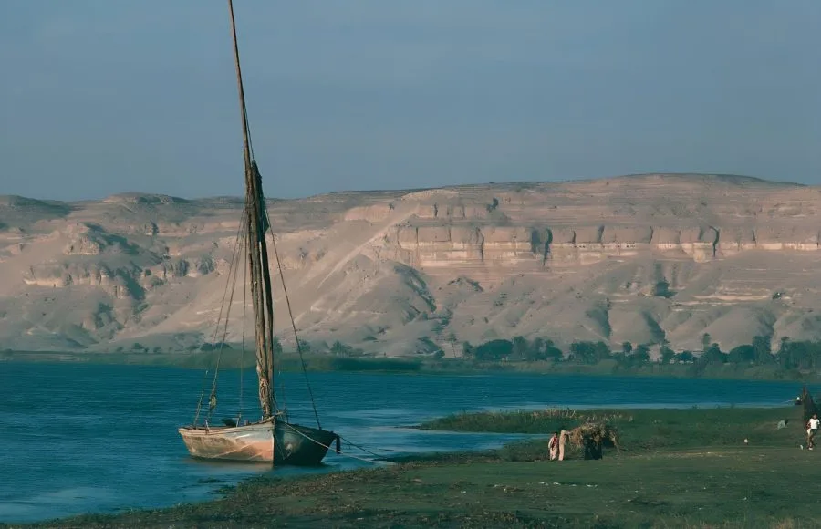 Nile felucca moored at Tel el-Amarna with desert cliffs towering in the background.