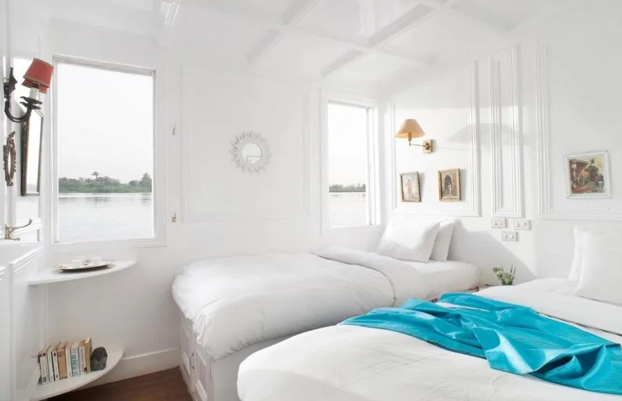 Bright twin-bed cabin on a Dahabiya Nile cruise with large windows overlooking the river.