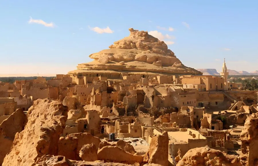 An imposing view of the ruined mud-brick fortress known as Old Shali, Siwa Oasis, built on a small rocky hill that dominates the surrounding structures in the desert.
