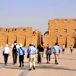 Tourists walk towards the monumental stone structures of the Karnak Temple Complex in Luxor, Egypt