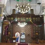 Ornate interior of the Samanoud and Saint Abanoub Church, decorated with a wooden screen and Coptic icons.