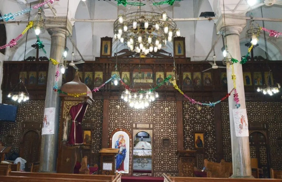 Ornate interior of the Samanoud and Saint Abanoub Church, decorated with a wooden screen and Coptic icons.