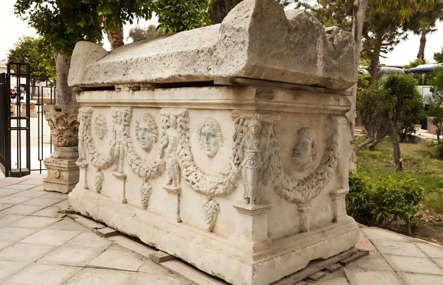Elaborately carved stone sarcophagus featuring masks and garlands outside the Catacombs of Kom El Shoqafa in Alexandria, Egypt.