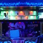 Bartender serving at the vibrant "The Disco Night" lounge bar on a Scarabee Nile Cruise.