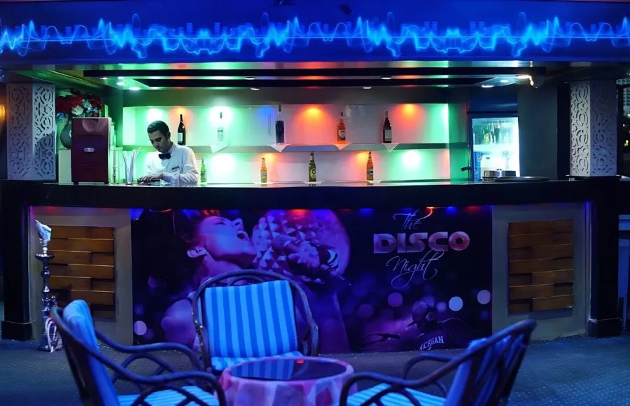 Bartender serving at the vibrant "The Disco Night" lounge bar on a Scarabee Nile Cruise.