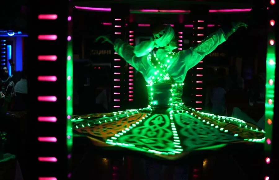A traditional Egyptian Tanoura dancer performing with glowing LED lights on a cruise.