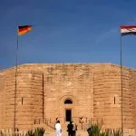 Exterior view of the imposing German War Graves Memorial in El Alamein, Egypt, featuring the German and Egyptian flags.
